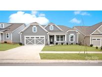 Charming gray home with a two-car garage and beautiful landscaping, set against a bright blue sky at 4440 Moxie Way, Charlotte, NC 28215