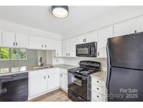 Bright kitchen features white cabinets, granite countertops and black appliances at 9424 Lexington Cir # F, Charlotte, NC 28213