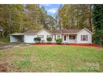 Charming ranch-style home with a one-car garage, carport, red mulch beds, and a well-manicured lawn at 113 Julius Ln, Mooresville, NC 28117