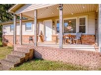 Inviting front porch with brick steps, wooden posts, and seating area at 316 Brawley Rd, Cleveland, NC 27013