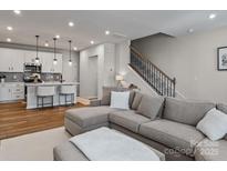 Open floor plan boasts a modern kitchen island and spacious living room with L-shaped sectional sofa at 118 Berkeley Ave # D, Mooresville, NC 28117