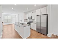 Bright kitchen boasts an island with sink, stainless steel appliances, and lots of white cabinets at 4018 Capital Ridge Ct, Charlotte, NC 28205
