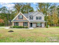 Charming two-story home featuring brick and gray siding, complemented by a well-manicured lawn and mature trees at 3018 Corinth Church Rd, Monroe, NC 28112