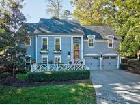 Charming two-story home featuring blue siding, mature trees and a two-car garage with a well manicured lawn at 94 Heritage Dr, Lake Wylie, SC 29710