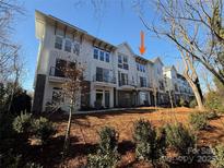 A row of modern townhomes showcases a blend of white siding and brick accents under a clear blue sky at 1419 Collier Walk Aly # Csw0208, Charlotte, NC 28205