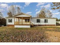 White single-wide mobile home with wooden deck and landscaped yard at 1176 Peppertree Dr, Mount Holly, NC 28120