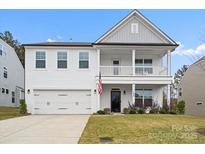 Charming two-story home featuring a welcoming front porch and attached two-car garage at 122 W Heart Pine Ln, Statesville, NC 28677