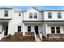 Charming two-story townhome featuring white siding, a dark front door, and a welcoming entryway at 105 Ciara Pl # B, Mooresville, NC 28117