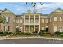 Charming brick townhouse with white columns, two-story porch, and manicured landscaping at 8336 Indigo Row, Charlotte, NC 28277