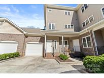 Three-story townhome with brick and siding exterior, attached garage, and front porch at 18819 Cloverstone Cir, Cornelius, NC 28031