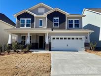 Two-story home featuring gray and blue siding, white trim, a two-car garage, and stone accents on the columns at 3031 Puddle Pond Rd # Lot 662, Indian Trail, NC 28079