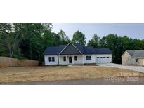 Charming home featuring white siding, a dark roof, and an attached garage nestled amongst mature trees at 536 Robinhood Rd # 27, Maiden, NC 28650