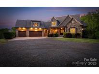 Stunning stone and brick home featuring a spacious three-car garage and manicured landscaping at 3678 Rankin Rd, Concord, NC 28027