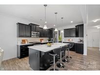 Modern kitchen with dark cabinets, white countertops, stylish pendant lighting, and bar stool seating at the island at 7618 Fenn Way, Indian Land, SC 29707