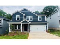 Charming two-story home with a two-car garage, dark blue siding, brick accents, and a well-manicured lawn at 122 Satchel Ct, Troutman, NC 28115