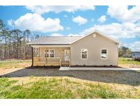 Tan home featuring a charming front porch with wood railing and a well-maintained yard under a partly cloudy blue sky at 501 Ed Wilson Rd, Bessemer City, NC 28016