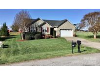 Charming single-story home featuring a well-manicured lawn, attached garage, and colorful landscaping at 120 W Edinburgh Ct, Statesville, NC 28625