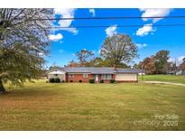 Charming brick single-story home featuring a well-maintained lawn and mature trees under a beautiful blue sky at 4501 Taylorsville Hwy, Statesville, NC 28625