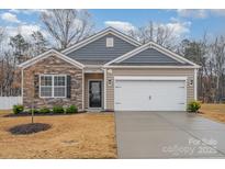 Charming single-Gathering home with stone accents, manicured lawn, and two-car garage at 654 Saddlebred Ln, Locust, NC 28097