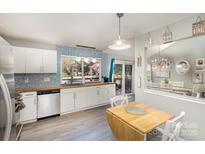 Bright kitchen boasts white cabinets, stainless appliances, butcher block counters and blue tile accents at 11800 Five Cedars Rd, Charlotte, NC 28226