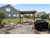 Relaxing backyard patio with pergola, seating area, and grill at 13929 Tilesford Ln, Huntersville, NC 28078