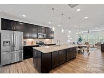 Modern kitchen featuring dark cabinets, stainless steel appliances, and a large granite island with pendant lighting at 208 Waterlynn Ridge Rd # B, Mooresville, NC 28117