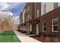 Modern brown brick townhouses with white accents, landscaping, and a walkway at 2216 Noble Townes Way, Charlotte, NC 28262