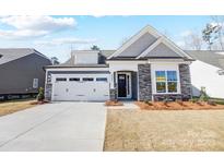 Charming single-Gathering home featuring stone accents, a two-car garage, and a well-manicured lawn at 4021 Grace Pointe Dr # 104, Wesley Chapel, NC 28079