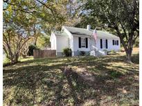 Charming single-story home featuring white siding, a green roof, and a manicured front lawn in a leafy neighborhood at 2100 Temple St, Kannapolis, NC 28081