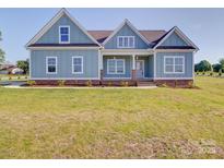 Charming light blue home featuring a well-manicured lawn and inviting front porch at 220 W Lawyers Rd, Monroe, NC 28110