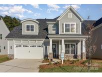 Charming two-story home features a grey exterior, well-manicured lawn, and inviting front porch at 1378 Cedardale Ln, Denver, NC 28037