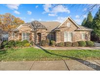 Charming single-story brick home featuring manicured landscaping and an inviting entrance, complete with shuttered windows at 14700 Old Vermillion Dr, Huntersville, NC 28078