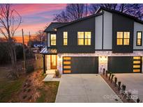 Modern two-story townhome exterior features stone accents and black garage doors at twilight at 2201 Catalina Ave, Charlotte, NC 28206