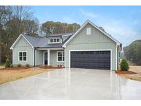 Charming single-story home features a stylish garage door, complemented by lush landscaping and a well-manicured lawn at 3007 Buffett Ln, Monroe, NC 28110