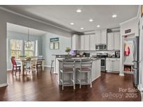 Open kitchen with island seating, stainless appliances, and adjacent dining area with natural light at 7520 Berkeley W Rd, Denver, NC 28037