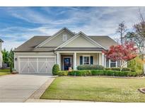 Tan two-story house with a two-car garage, manicured lawn, and landscaping at 1035 Crescent Moon Dr, Fort Mill, SC 29715
