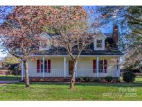 Charming yellow home with dormer windows, brick foundation and front porch with red shutters at 2216 Lowell Bethesda Rd, Gastonia, NC 28056