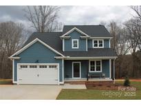 Charming two-story home with blue siding, white trim, a cozy front porch and a two-car garage at 2668 Polo Ln, Maiden, NC 28650