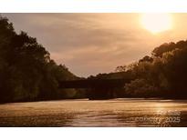 Scenic water view featuring a bridge beneath a radiant sunrise, framed by lush trees at 294 Carroll Cv, Clover, SC 29710