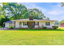 Charming single-story home with brick chimney and a well-manicured front lawn and covered porch with rocking chairs at 2005 Robyn Ave, Shelby, NC 28152