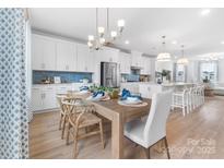 Bright open-concept dining room featuring modern lighting, light wood floors, and seating for six at 2146 Barrowcliffe Nw Dr, Concord, NC 28027