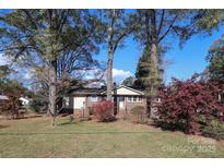 Brick ranch house with a landscaped lawn and mature trees at 2701 Palm Ave, Charlotte, NC 28205