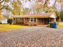 Charming brick ranch-style home with a gravel driveway and lush landscaping at 1905 26Th Ne St, Hickory, NC 28681