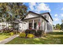 Charming two-story home featuring a covered porch, American flag, and well-manicured landscaping at 511 E Main St, Rock Hill, SC 29730