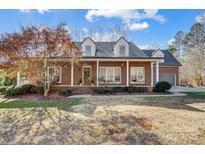 Charming brick home with a metal roof, dormer windows, and a welcoming front porch at 6610 Rolling Ridge Dr, Waxhaw, NC 28173