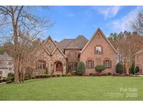 Elegant brick and stone home with lush lawn, mature trees, and architectural roof details at 1716 Funny Cide Dr, Waxhaw, NC 28173
