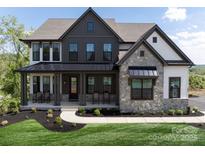 Striking two-story home featuring stone accents, dark siding, and a welcoming front porch with comfortable rocking chairs at Lot 42 Watercourse Way # Hawthorne, Belmont, NC 28012