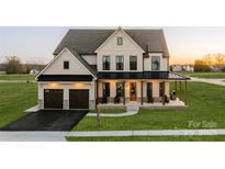 Stunning two-story home featuring a covered porch, attached garage, and manicured lawn at Lot 47 Watercourse Way # Devonshire, Belmont, NC 28012