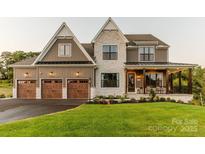 Two-story house with stone and brown siding, three-car garage, and landscaped yard at Lot 51 Watercourse Way # Nottingham, Belmont, NC 28012