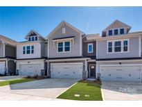 Charming townhomes featuring a two-car garage, neutral siding, and manicured lawns on a sunny day at 157 Halite Ln, Waxhaw, NC 28173